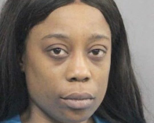 Mugshot of a woman with long black hair wearing a teal shirt.