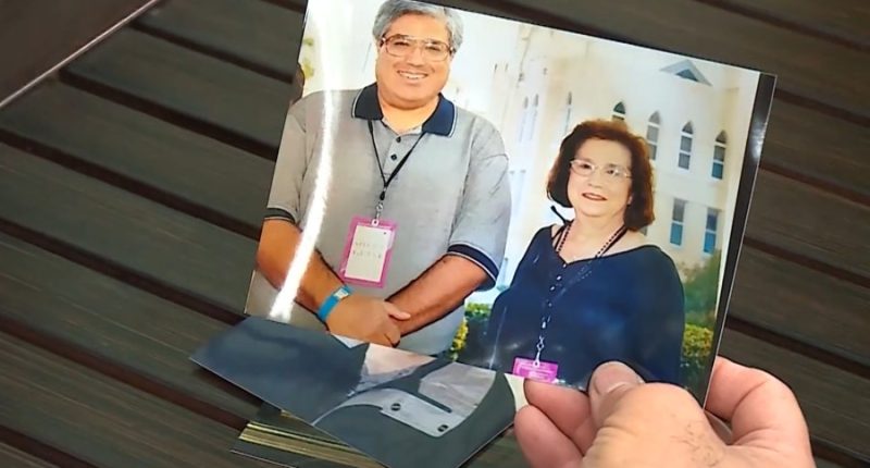 person holding photo of man and woman