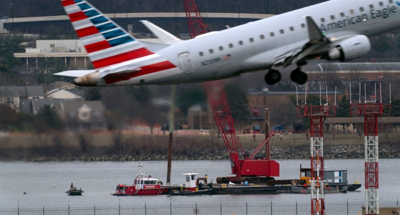 An American Eagle jet passes as rescue and salvage crews work near the wreckage of an American Airlines jet in the Potomac River from Ronald Reagan Washington National Airport, Sunday, Feb. 2, 2025, in Arlington, Va. (AP Photo/Jose Luis Magana)