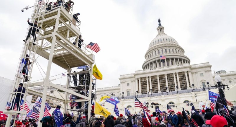 FILE - Violent insurrectionists breach the U.S. Capitol in Washington, Jan. 6, 2021. A former government employee has been charged with repeatedly submitting fake tips to the FBI reporting that several of his co-workers in the intelligence community were part of a mob that attacked the U.S. Capitol on Jan. 6. Court records unsealed on Friday, May 3, 2024, say that Miguel Eugenio Zapata was arrested in Chantilly, Virginia, on Thursday on a charge that he made false statements to law enforcement. (AP Photo/John Minchillo, File)
