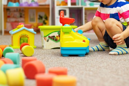 Child playing with colorful toys at daycare / childcare or in kindergarten.