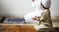Little boy praying alongside his father during Ramadan Eid Muslim Islam