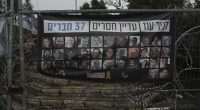 A poster shows portraits of Bibas family, top row from second left: Yarden, Shiri, and their sons Ariel and Kfir, who were kidnapped to Gaza on Oct. 7, 2023, in Jerusalem, Friday, Feb. 21, 2025. Letters on top read, "37 members of Kibbutz Nir Oz are still missing". (AP Photo/Mahmoud Illean)