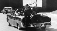 Secret Service Agent Clint Hill rides on the back of the presidential limousine after President John F. Kennedy was fatally shot in Dallas, Texas, on November 22, 1963. First lady Jacqueline Kennedy leans over the president.