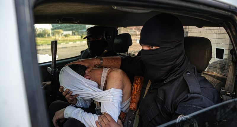 Syrian security forces detaining a man in a vehicle.
