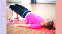fit brunette woman doing a glute bridge exercise on mat in workout space