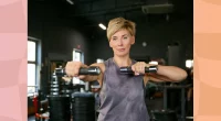 fit middle-aged woman lifting dumbbells in dark gym weight room