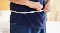 Close Up Of Overweight Man Measuring Waist