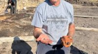 Volunteer holding a 1,000-year-old Pictish ring at an archaeological dig.