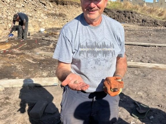 Volunteer holding a 1,000-year-old Pictish ring at an archaeological dig.
