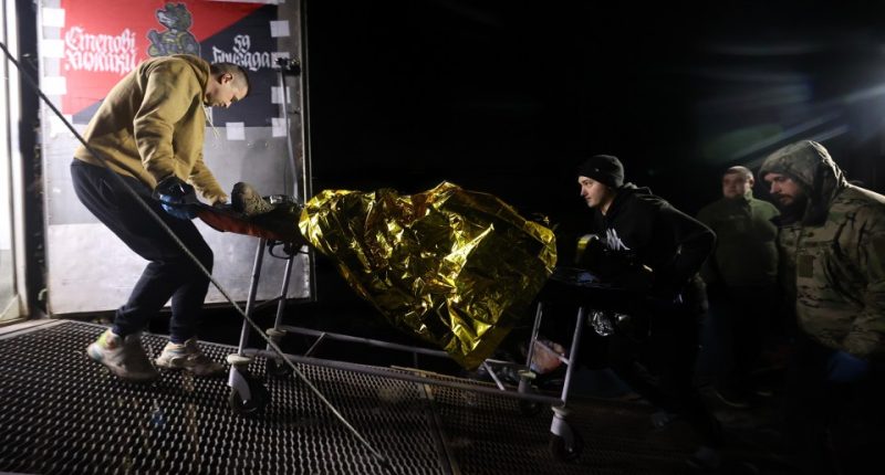Wounded soldier being wheeled into a mobile field hospital.
