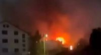 Nighttime view of a large fire engulfing a building.