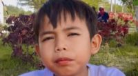 Boy eating satay outdoors.