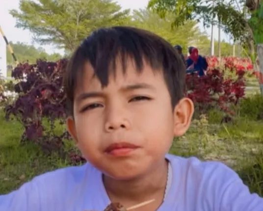 Boy eating satay outdoors.