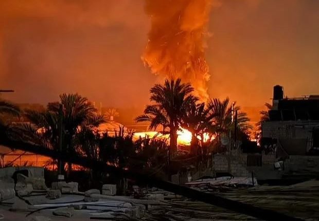 Large fire burning behind palm trees.