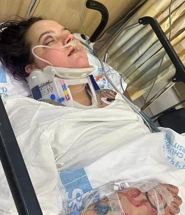 Woman in hospital bed wearing neck brace.