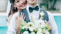 Newly married couple embracing, holding a bouquet.