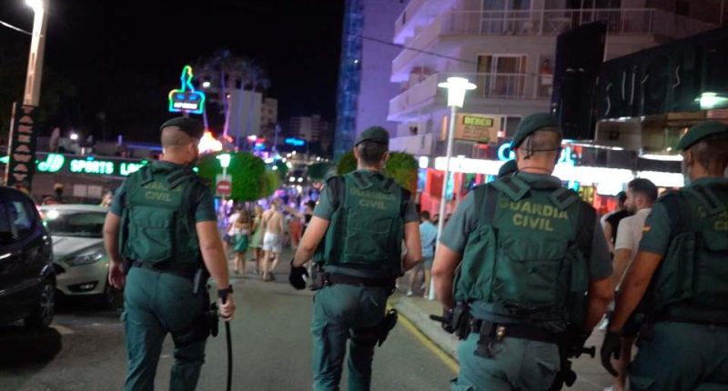 Guardia Civil officers patrolling a street at night.