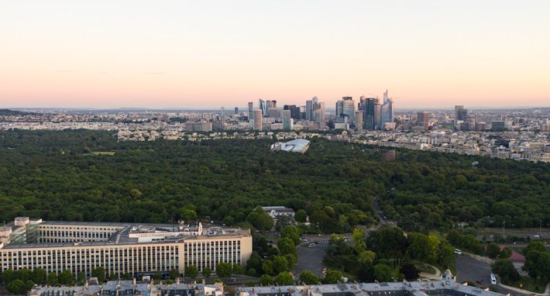 Aerial view of Paris skyline at sunrise, with La Defense in the distance.