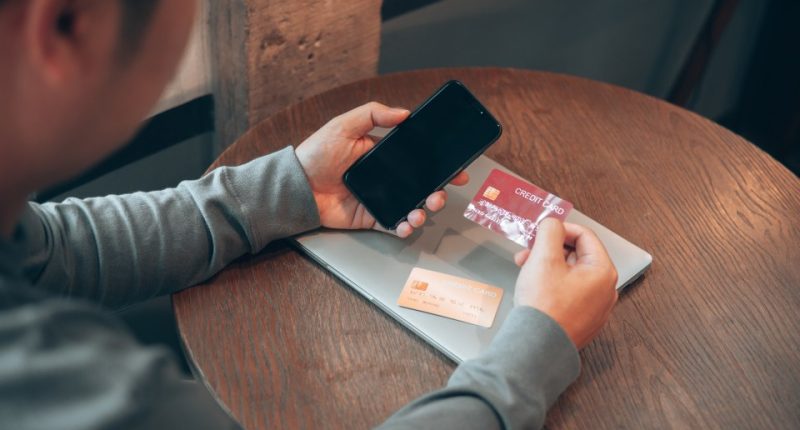 Man using phone and credit cards for online banking.