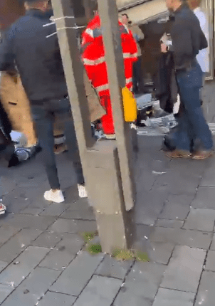 People standing around a paramedic in a red uniform.