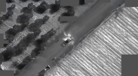Aerial thermal image of a vehicle explosion on a road.
