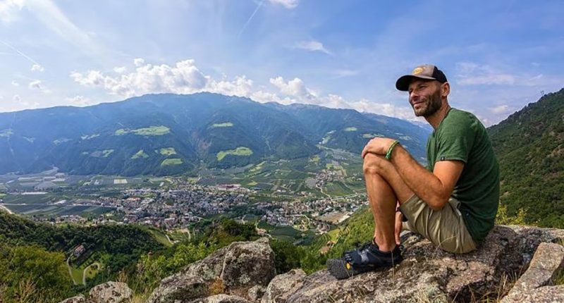 Robert Fliri sitting on a rock overlooking a valley.