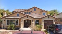 Two-story house with a terracotta tile roof and a large double door.