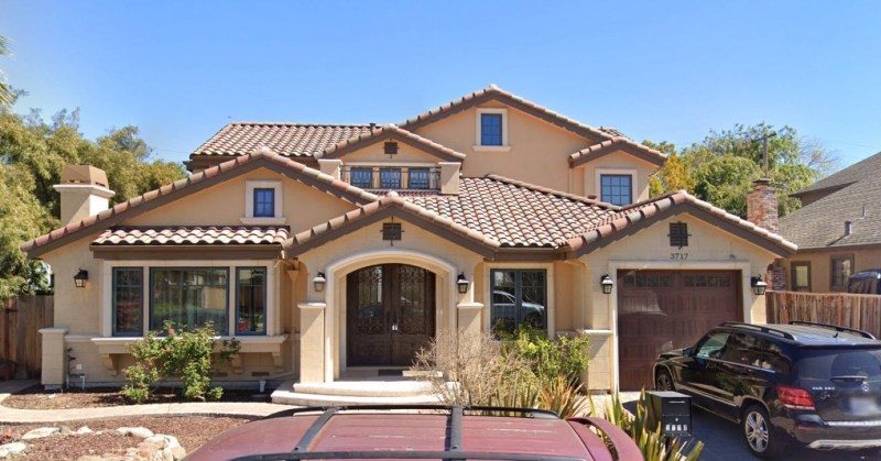 Two-story house with a terracotta tile roof and a large double door.
