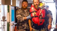 A navy medic assists a rescued long-distance rower aboard a ship.