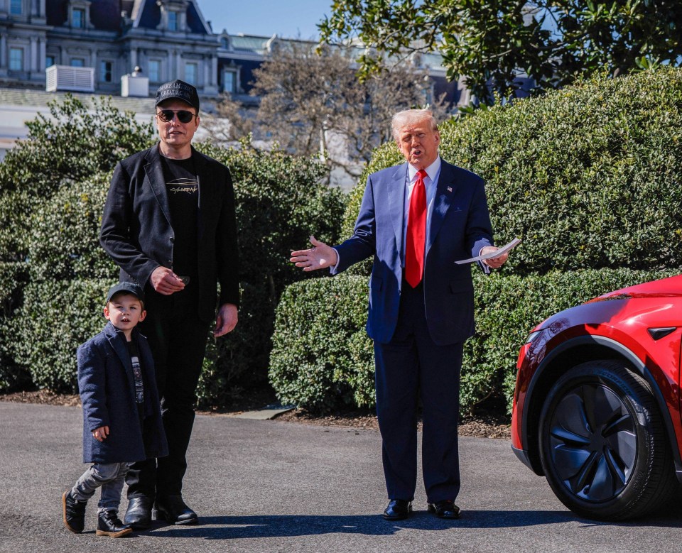 President Trump, Elon Musk, and his son X stand by a red Tesla.