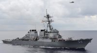 USS Curtis Wilbur guided-missile destroyer at sea with helicopter overhead.