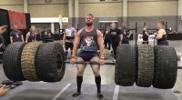 A strongman competitor lifting heavy tires during a competition.