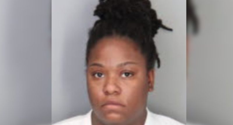 Mugshot of a woman with dark hair in a bun.