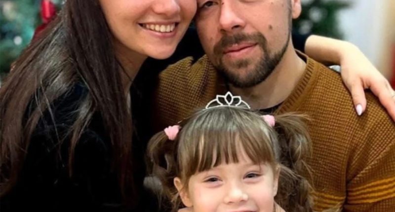 Photo of a family; a father, mother, and young daughter.