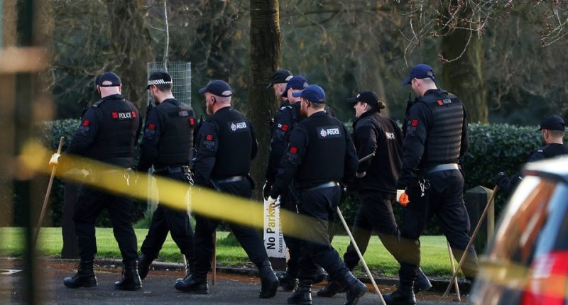 Police officers at a park crime scene.