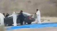 People in white suits loading a car.