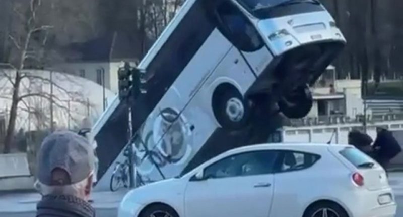 A bus has reversed into a river, striking a car and pedestrians.