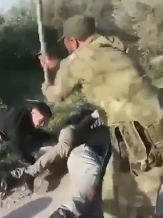 A soldier apprehending a person on the ground.