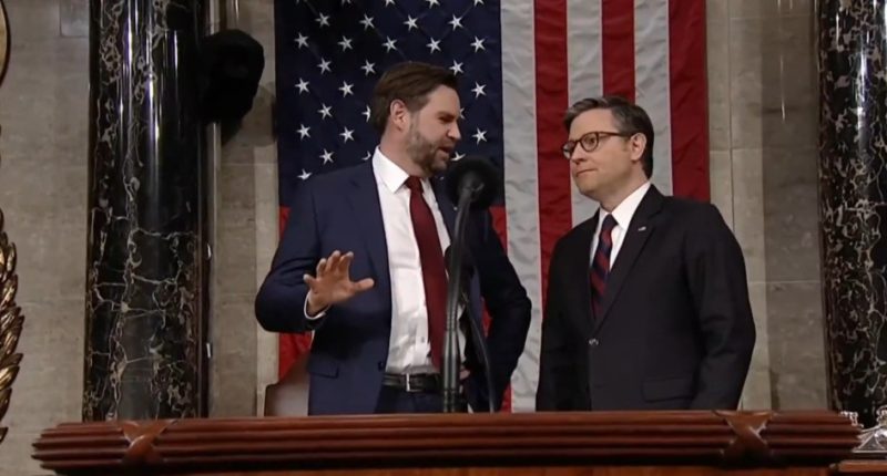 Two men in suits conversing at a podium in front of an American flag.