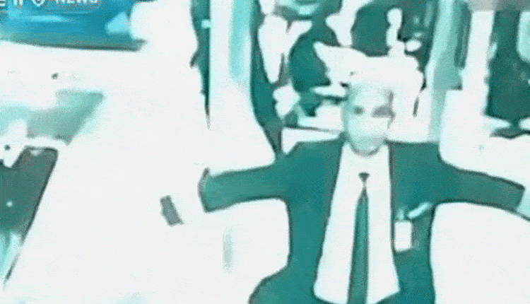GIF of a man in a suit appearing to walk through a crowd.