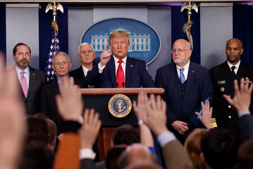 President Trump speaking at a White House press briefing about the coronavirus, surrounded by health officials.