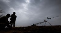 Silhouetted soldiers launching a drone.