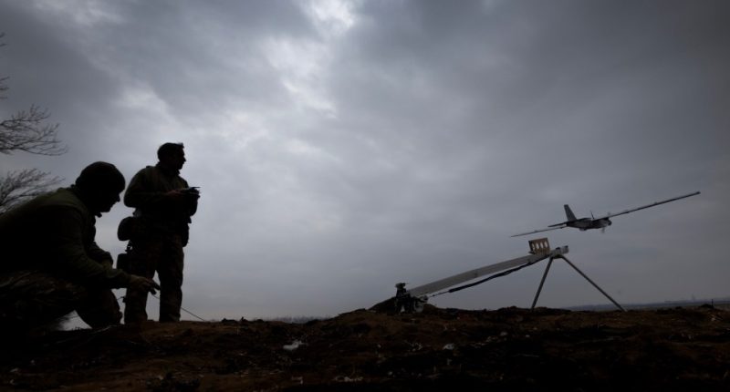 Silhouetted soldiers launching a drone.