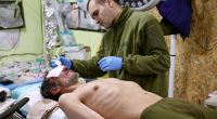 A medic treats a wounded Ukrainian soldier in a field hospital.