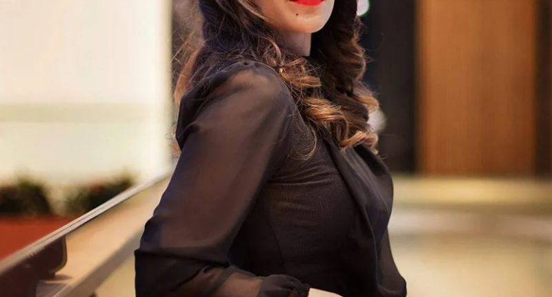 Woman in black shirt leaning on a railing.