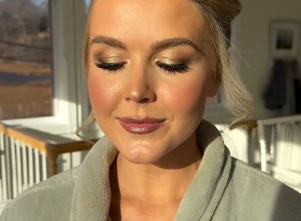 Woman in a robe with bridal makeup.