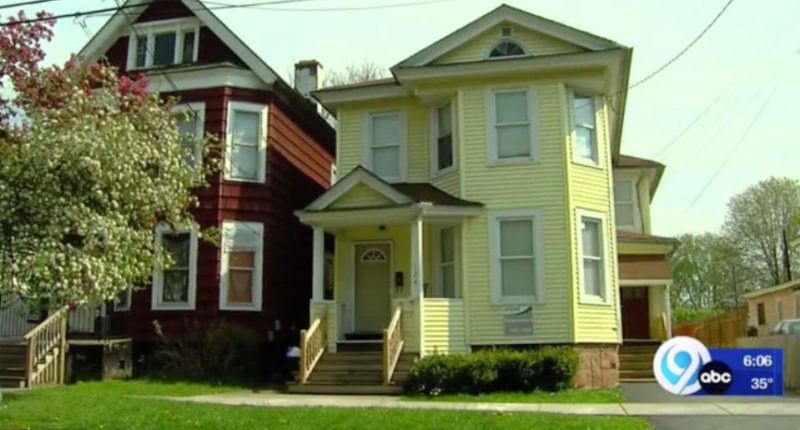 Two houses, one yellow and one red, on a residential street.