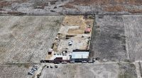 Aerial view of a crime scene in Mexico, showing vehicles and personnel from law enforcement agencies at a ranch where human crematoriums were discovered.