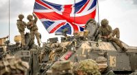 British soldiers on a military vehicle unfurl the Union Jack during a NATO exercise.